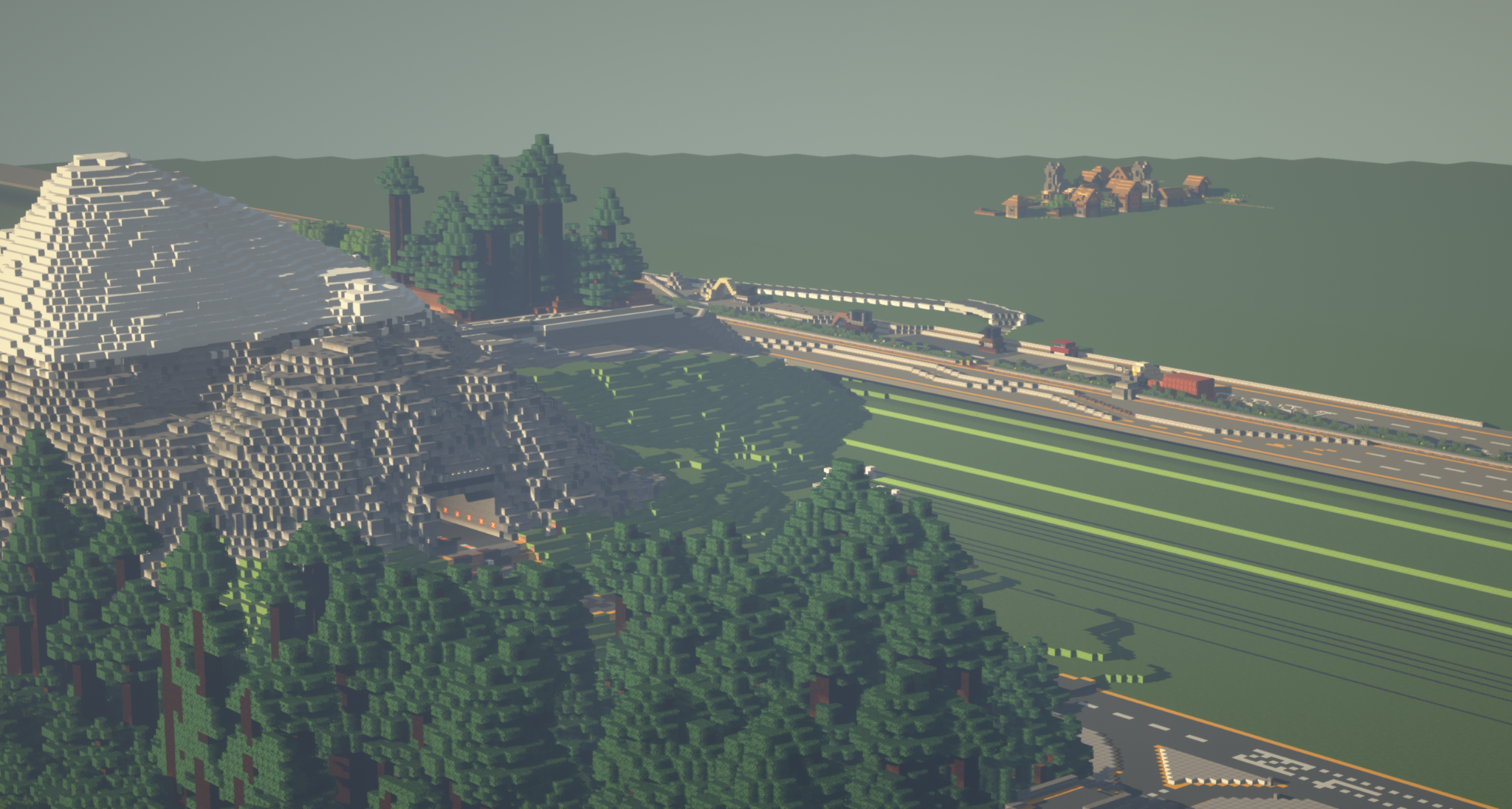 The picture shows a large mountain in the foreground, which is surrounded by a railroad line. The striking mountain with its pyramid-shaped peak is the dominant element of the image. A highway with several cars runs around the mountain, with cars driving on it. Other mountains and a small town can be seen in the background, adding to the varied landscape.